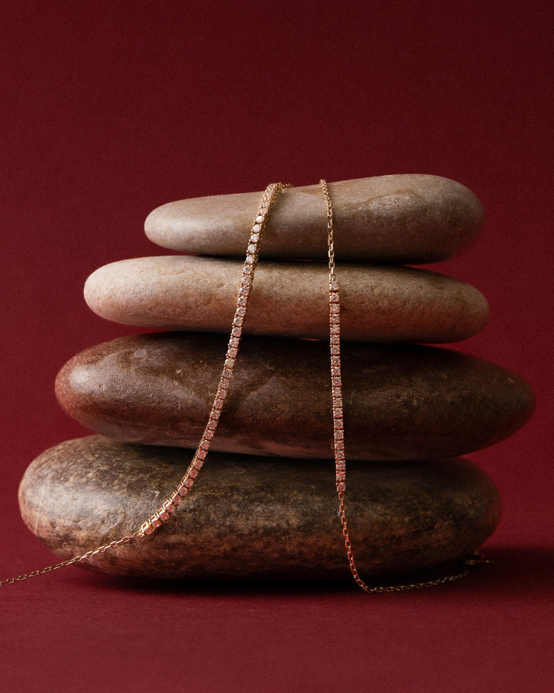 Anate gold diamond bracelet displayed on stacked natural stones, showcasing jewelry.