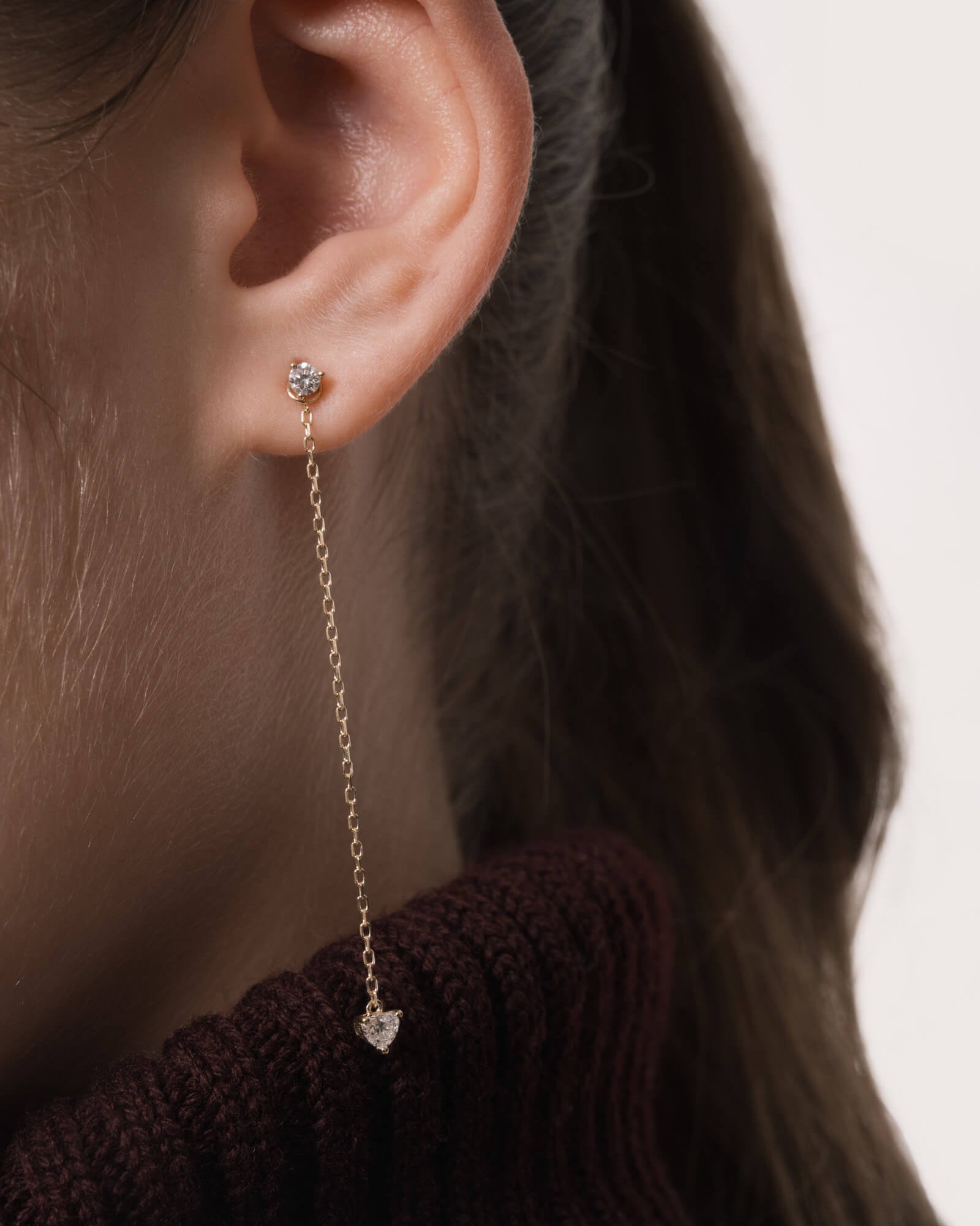 Model wearing the Raya heart diamond drop earrings in solid yellow gold by Anate, worn on ear