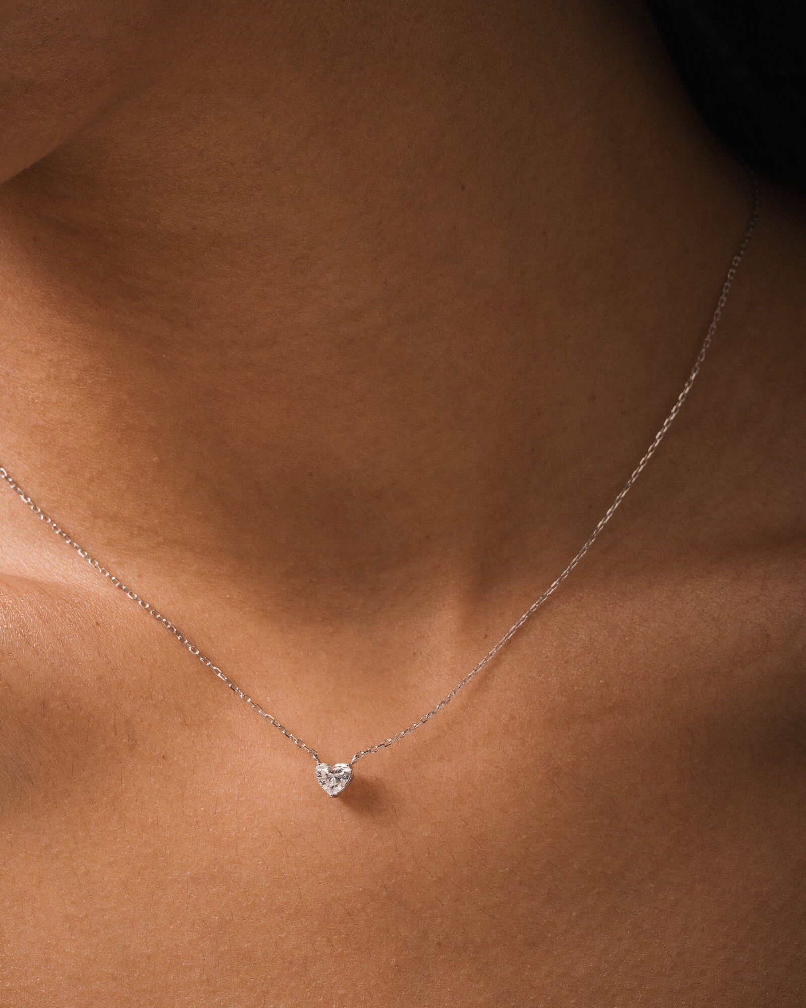 Model wearing the Lumi heart diamond pendant in solid white gold by Anate, worn on model, close-up