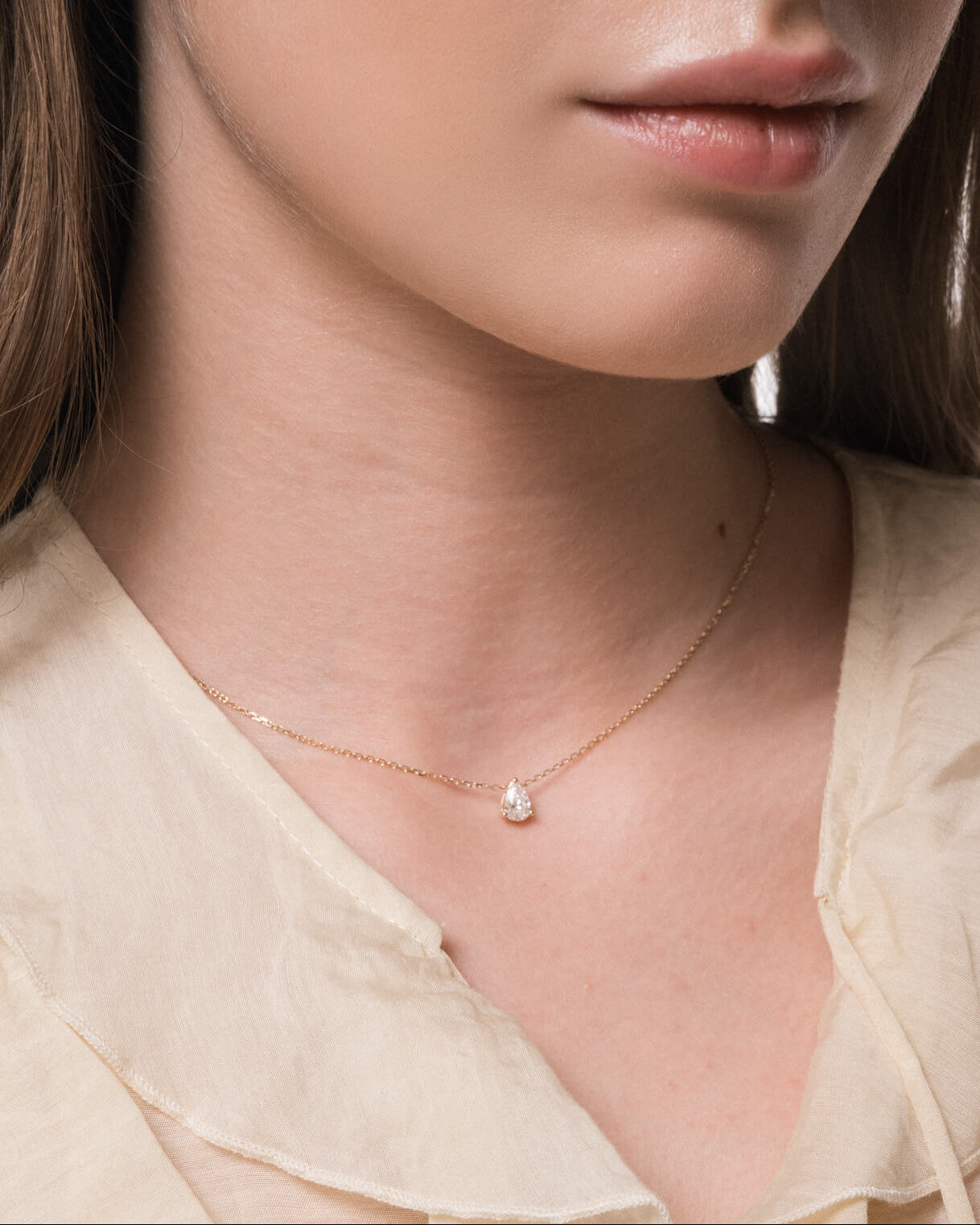Model wearing the Liora pear diamond pendant in solid yellow gold by Anate, worn on neck