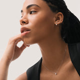 Model wearing the Elara reversible oval diamond pendant in solid white gold by Anate, worn on model, portrait shot