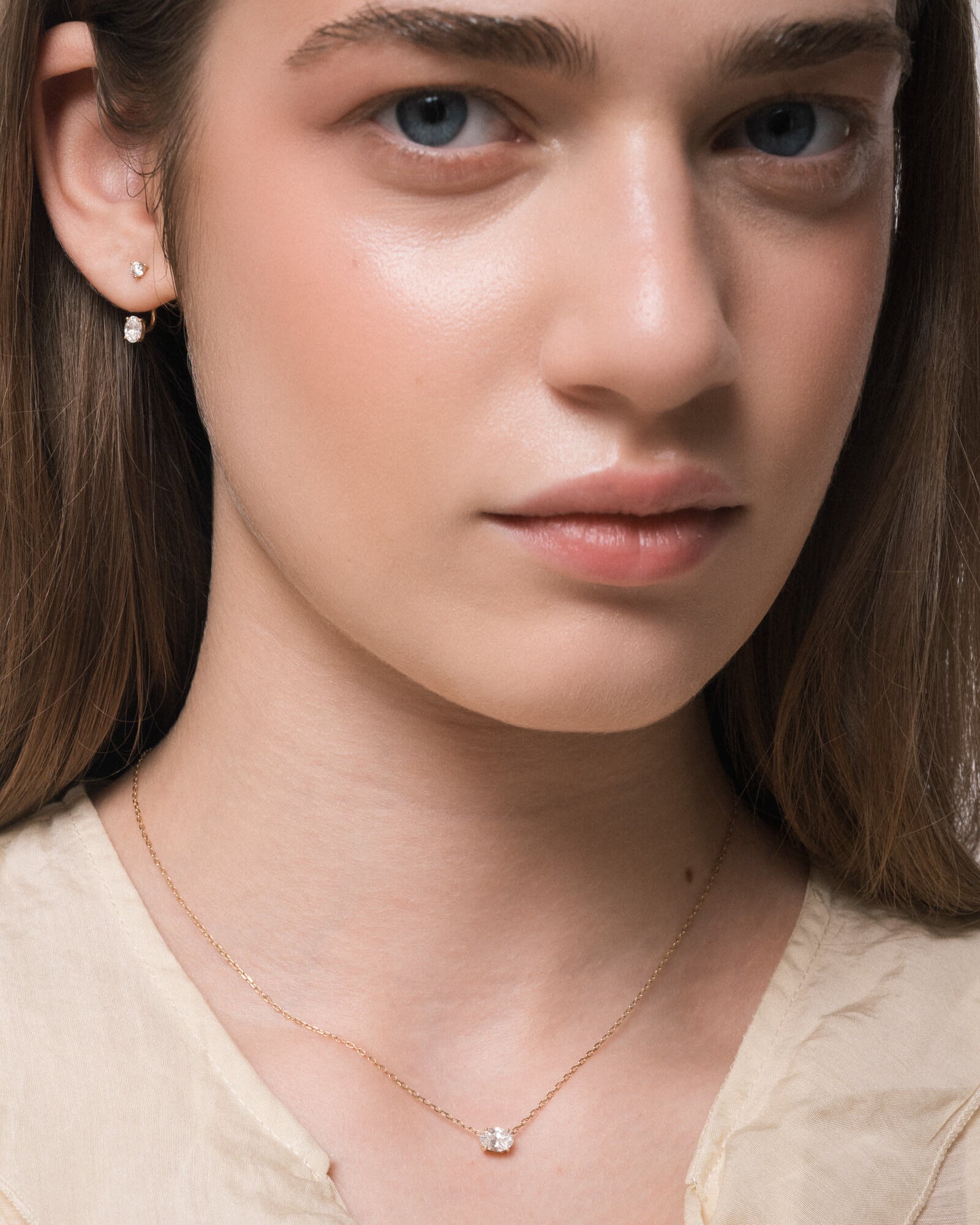 Model wearing the Elara reversible oval diamond pendant in solid yellow gold by Anate, horizontal orientation
