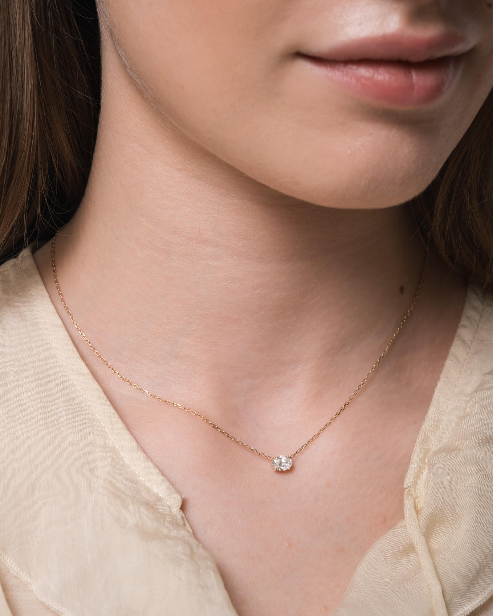 Model wearing the Elara reversible oval diamond pendant in solid yellow gold by Anate, worn on neck