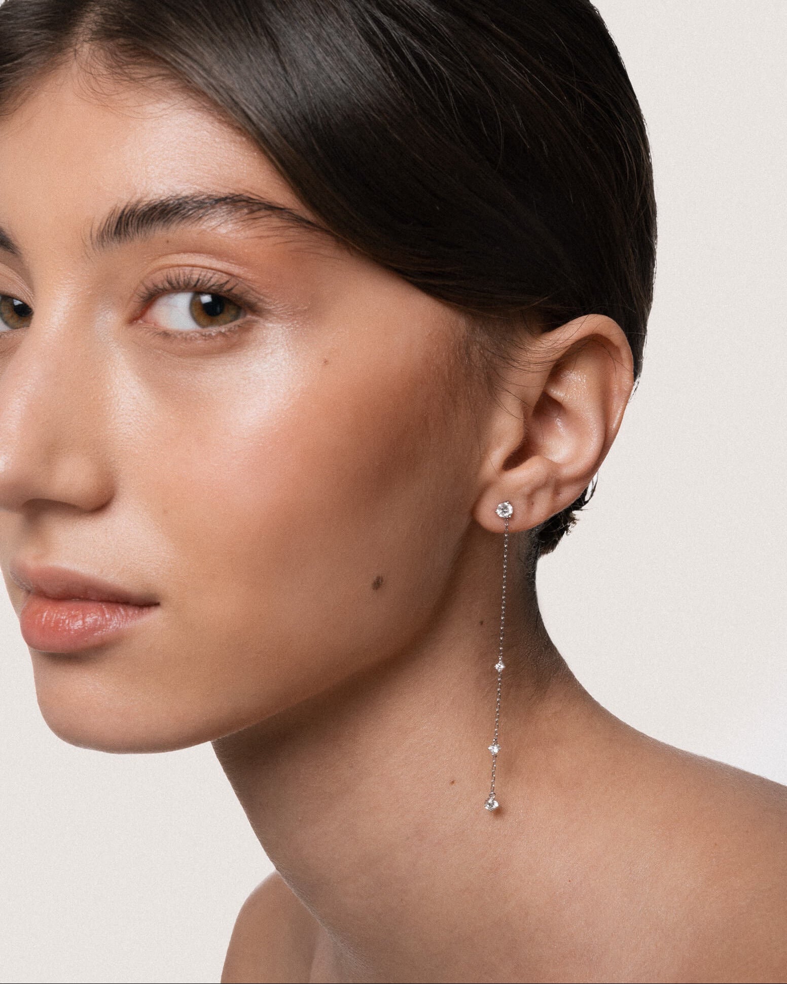 Model wearing the Aura round diamond drop earrings in solid white gold by Anate, worn on ear