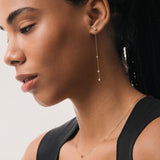 Model wearing the Aura round diamond drop earrings in solid yellow gold by Anate, worn on ear