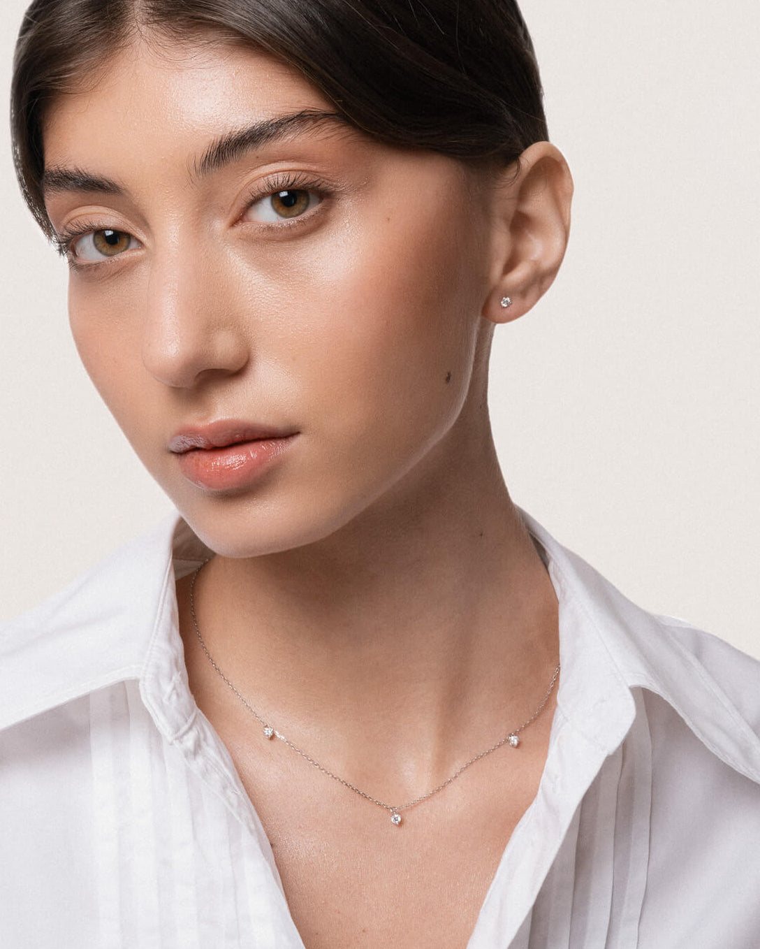 Model wearing the Elio three diamond necklace in solid white gold by Anate, worn on model, portrait shot